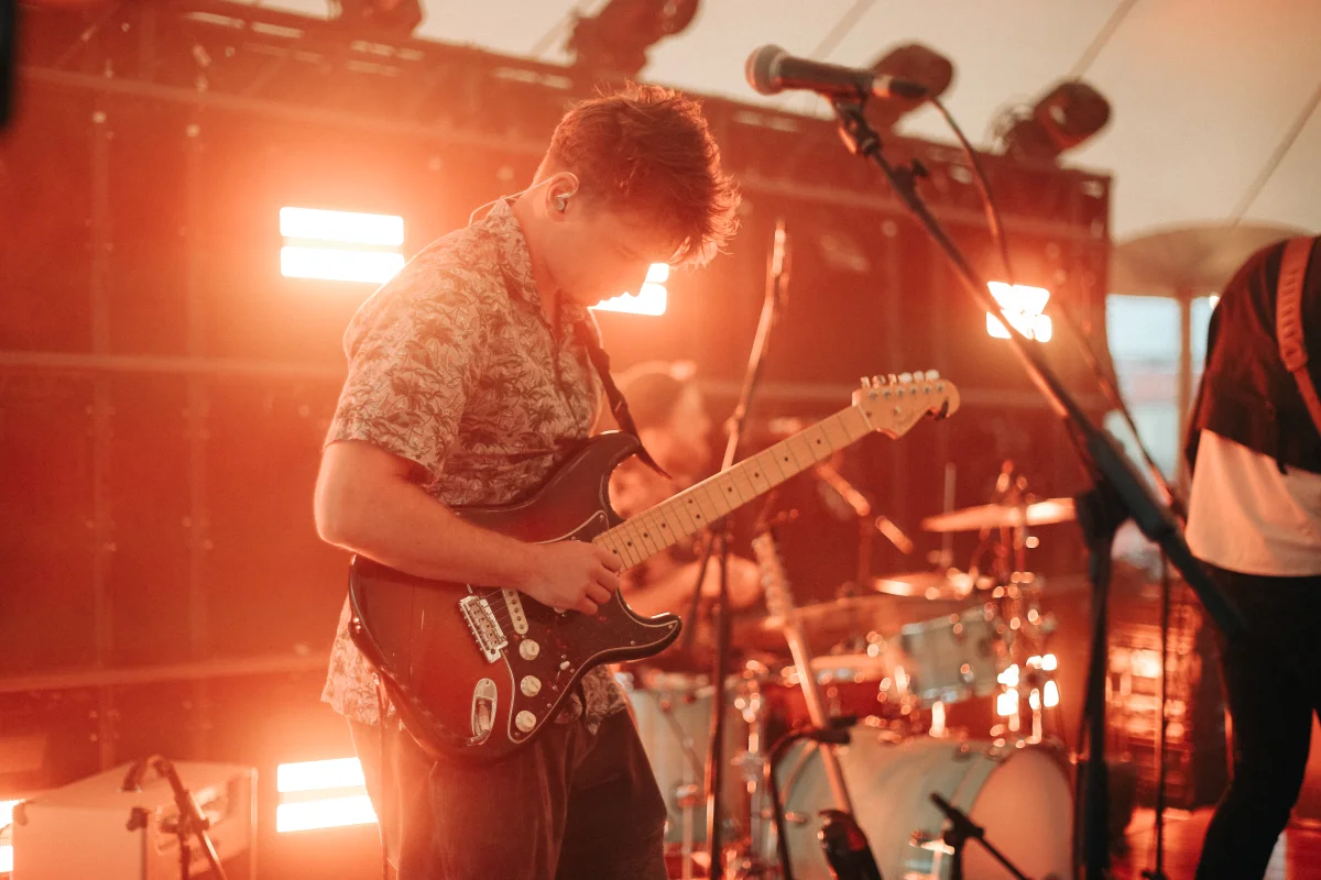 Kinmara guitarist performing live on stage under warm lights