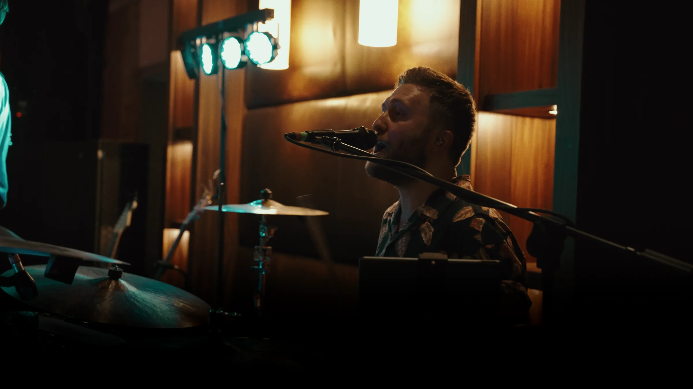 Kinmara performing at an evening event, drummer singing under stage lighting