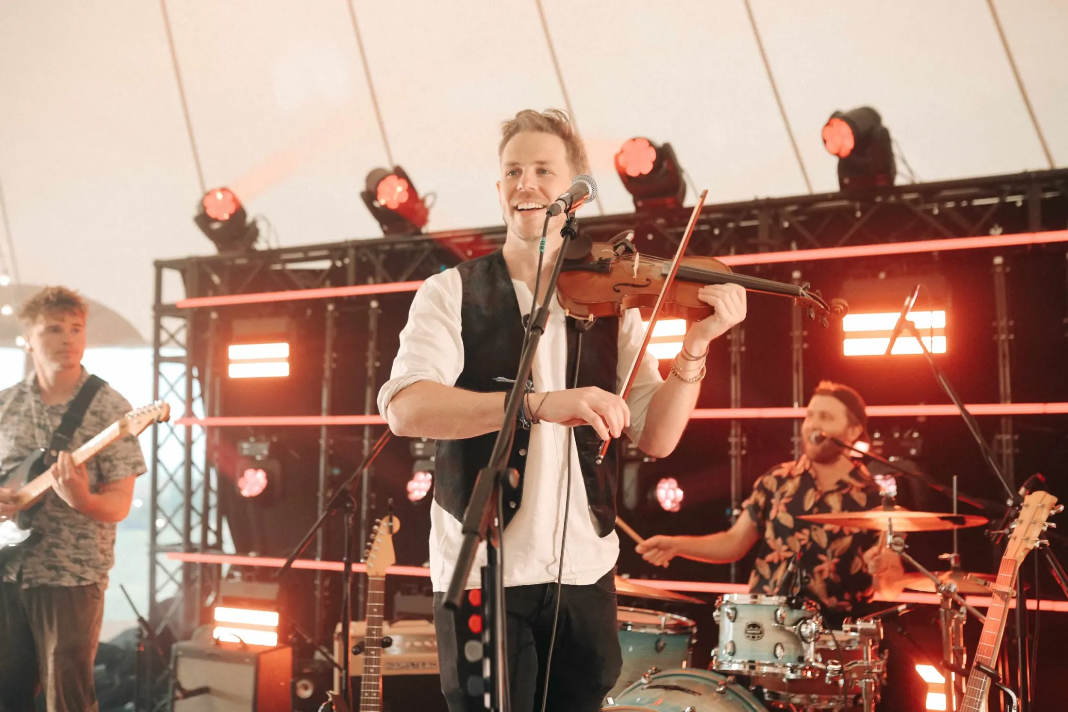 Kinmara's singer playing the fiddle on stage, with the band behind him