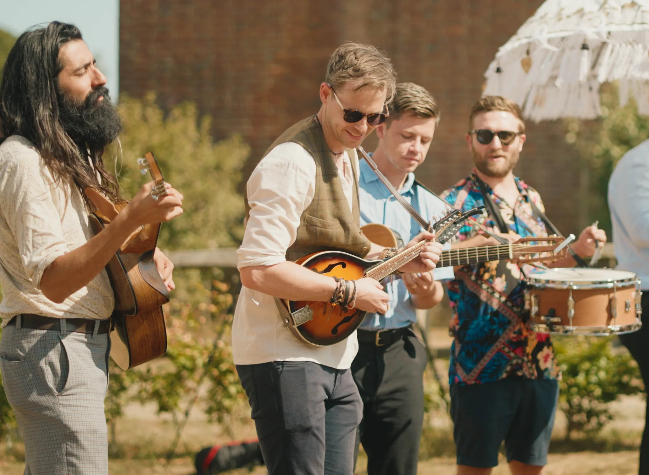 Kinmara playing an acoustic folk set outdoors with guitar, mandolin and snare drum