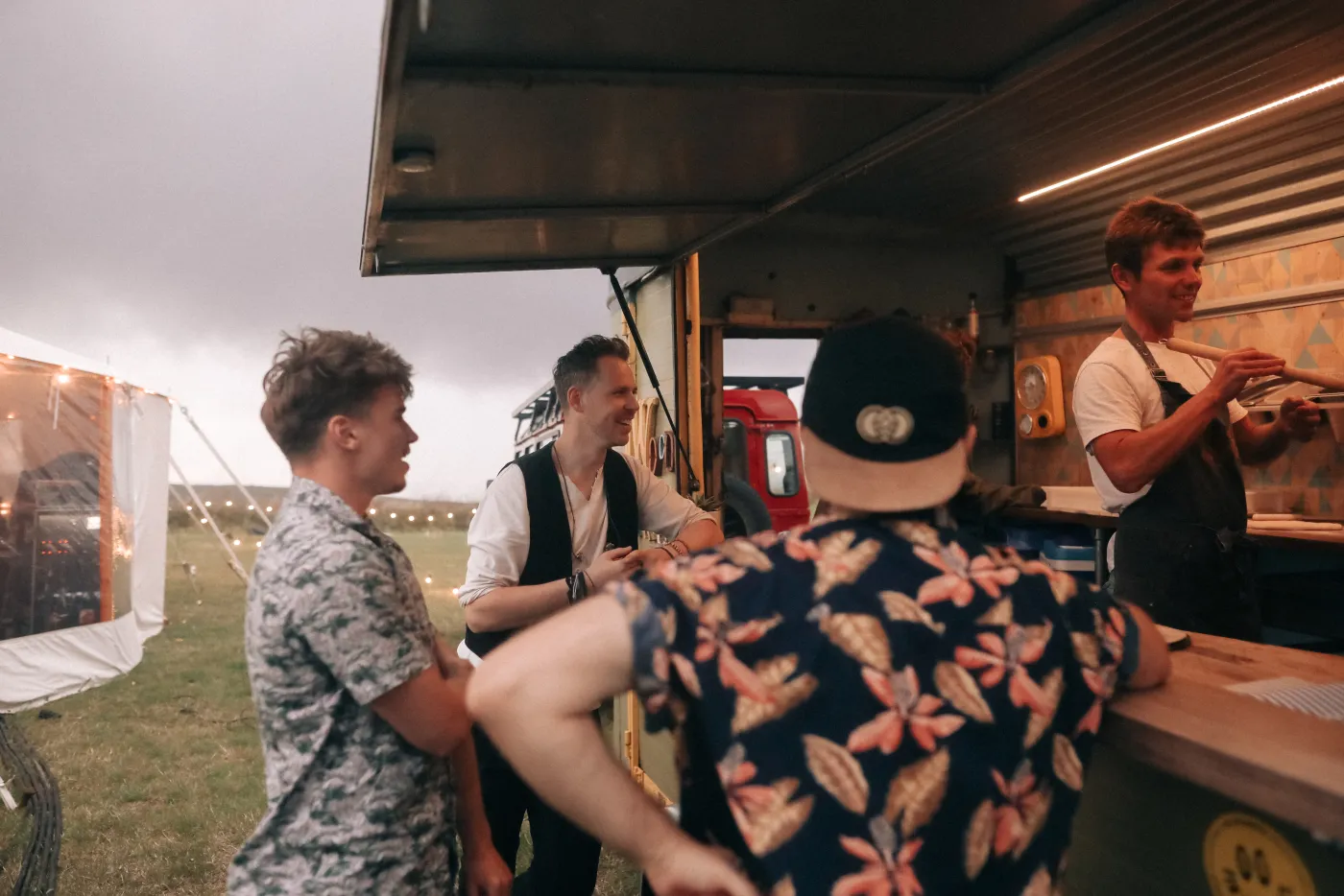 Kinmara musicians chatting beside a wood-fired food truck at a relaxed outdoor wedding