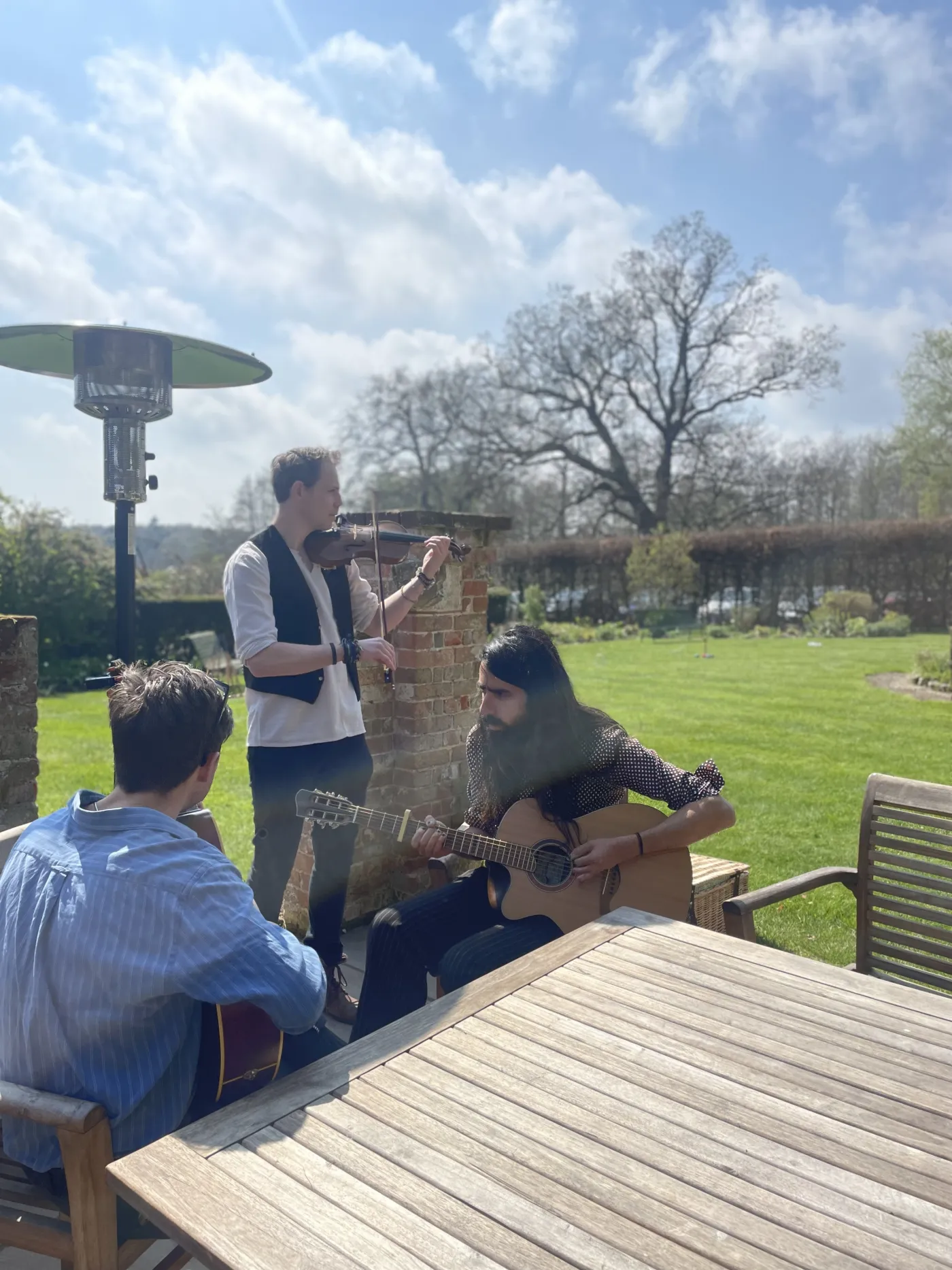 Acoustic set with violin and guitar performing in a sunny country garden