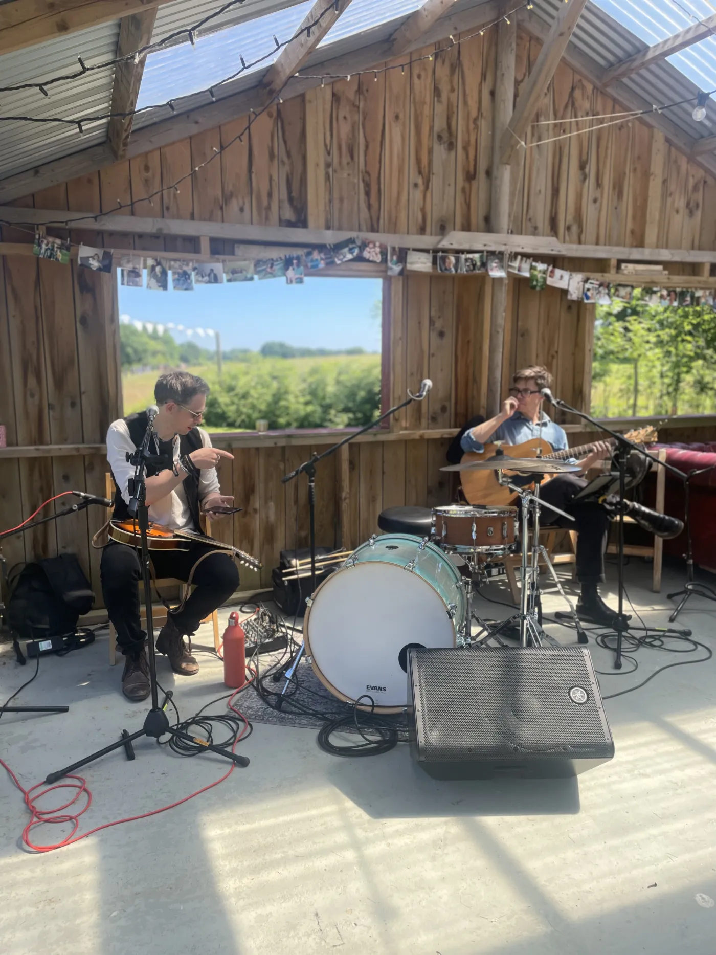 Acoustic duo playing guitar and mandolin in a sun-filled rustic barn