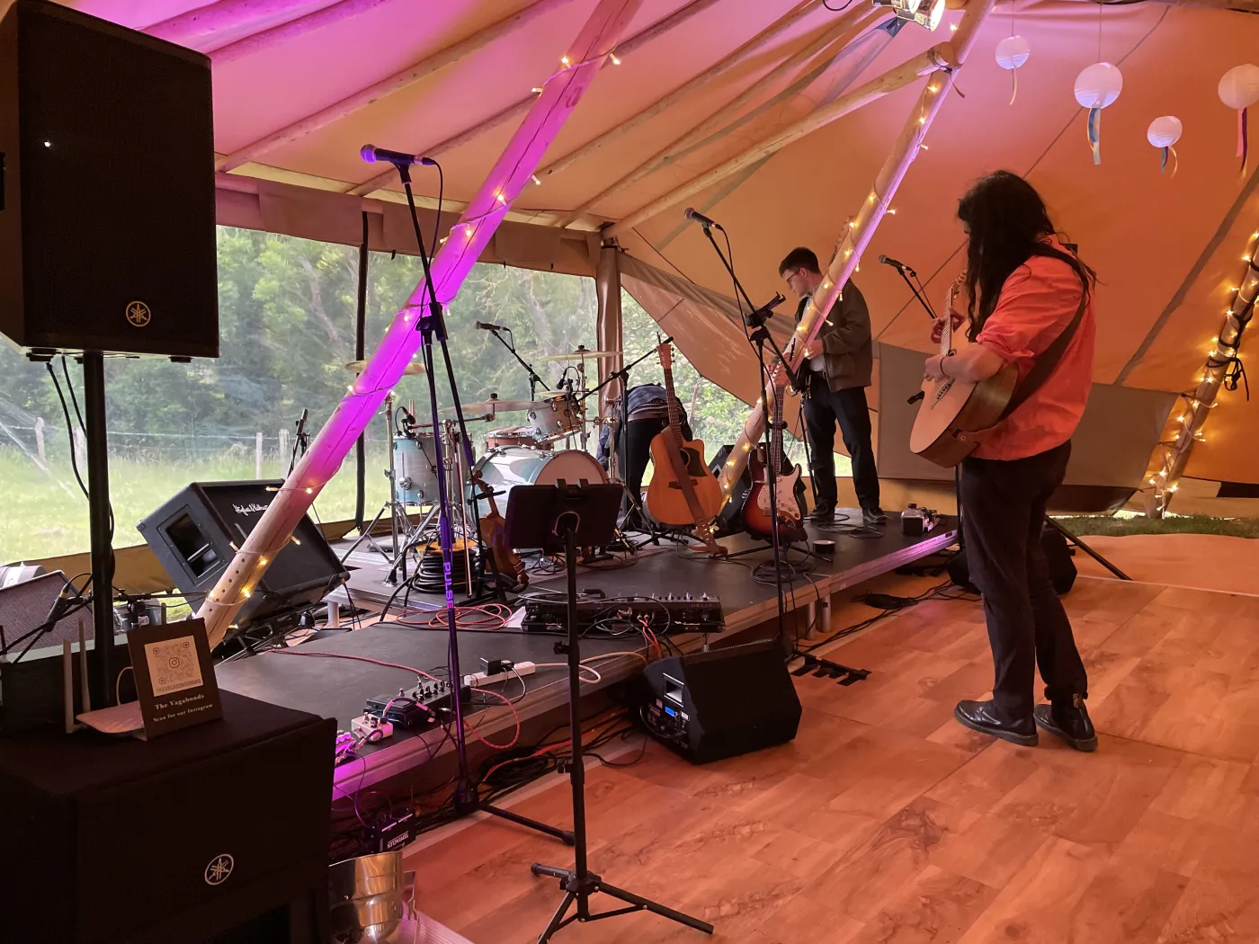 Kinmara on stage inside a tipi with warm lighting and acoustic guitars