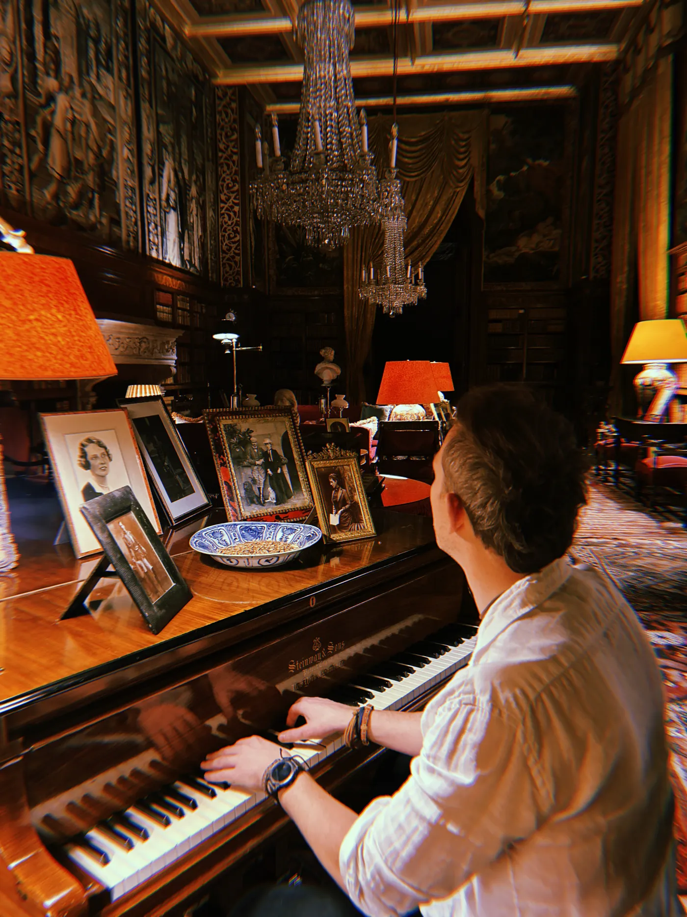 A pianist playing a grand piano in the library of a grand stately home