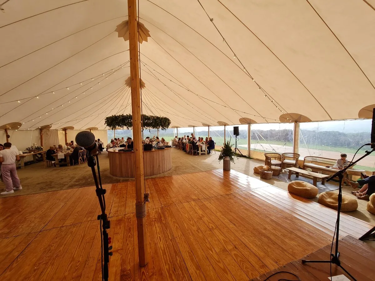 Inside a sperry tent: empty dancefloor and wedding guests seated at tables before the evening set