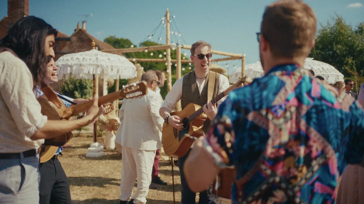 The band playing in a circle outdoors, fiddle and mandolin, guests gathered around