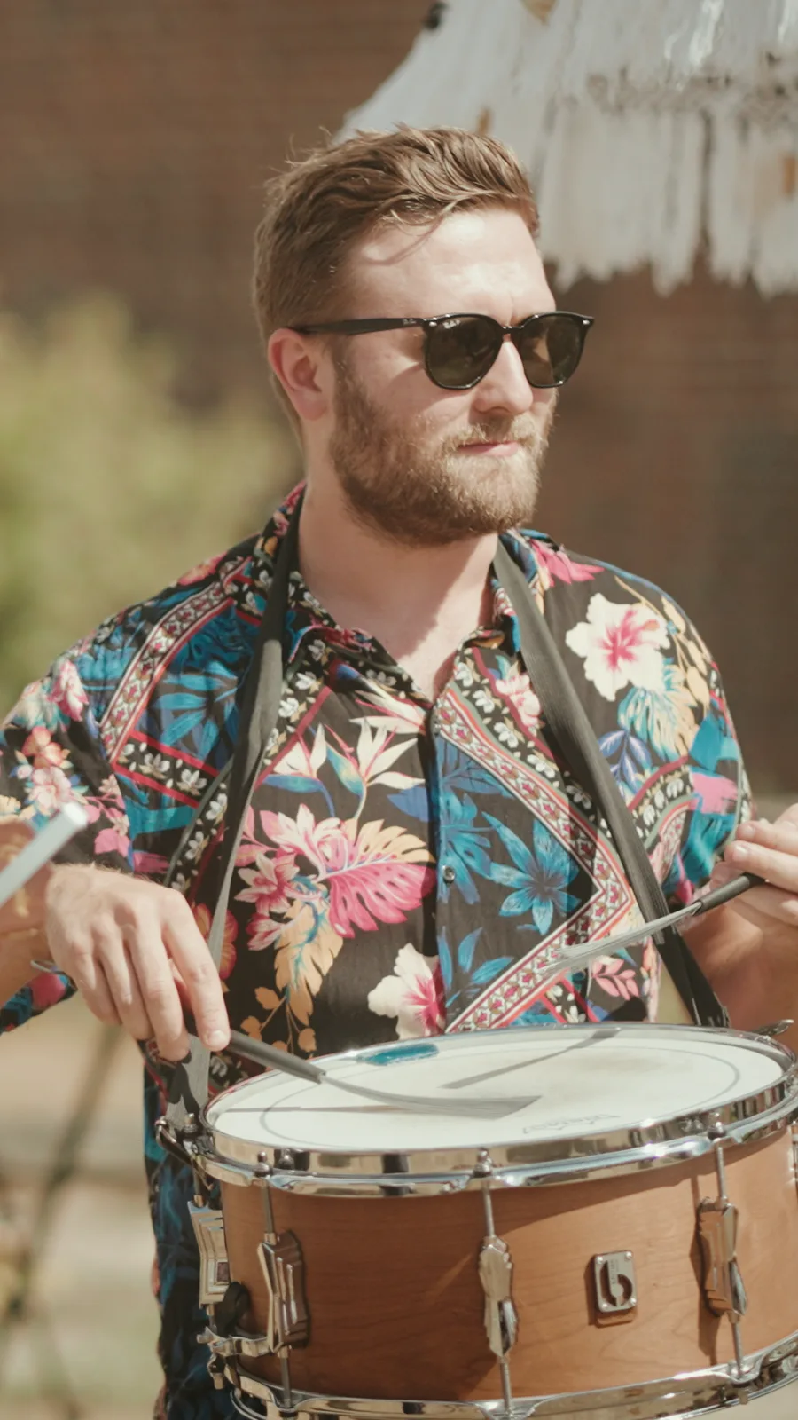 Kinmara's snare drummer in a bright floral shirt and sunglasses, playing in the sun