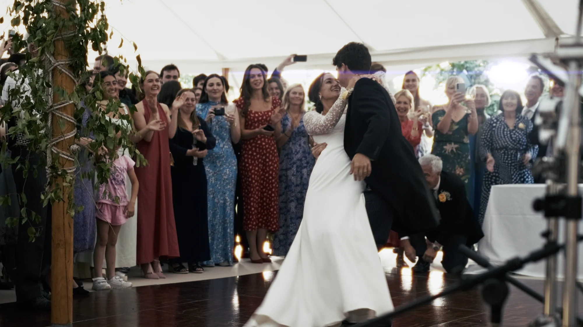 The same second of the same first dance from Kinmara's stage camera, showing both of the couple's faces and the guests reacting behind them