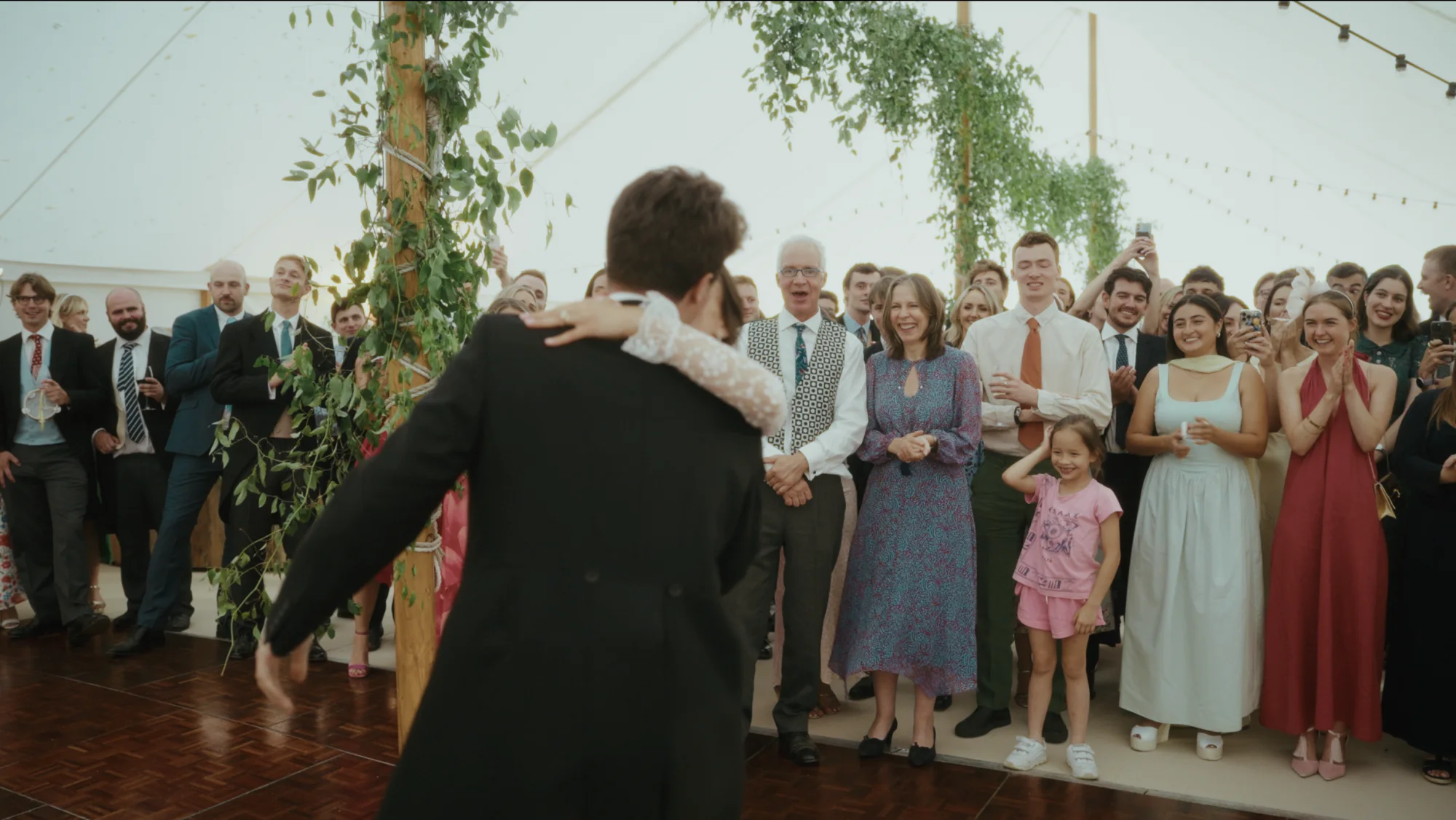 A couple's first dance from the videographer's position on the dancefloor, where the couple have turned away and their faces are hidden